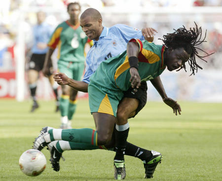 Senegal's Ferdinand Coly (R) and Uruguay's Mario Regueiro (L) collide as they fight for the ball during their World Cup Finals match in Suwon, June 11, 2002