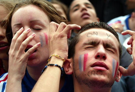 French soccer fans react in Paris as they watch the match between France and Denmark on a giant screen in the soccer World Cup June 11, 2002. France. Defending champions France went out of the World Cup finals in the first round after a 2-0 defeat by Denmark