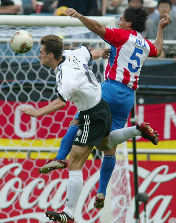Germany's Miroslav Klose and Paraguay's Celso Ayala go up for a header during their second round match at the World Cup finals in Sogwipo June 15, 2002.