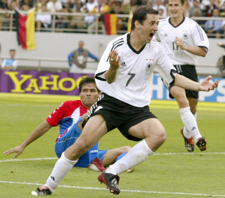 Germany's Oliver Neuville (7) celebrates scoring as Paraguay's Celso Ayala lies on the ground during their second round match at the World Cup finals in Sogwipo June 15, 2002