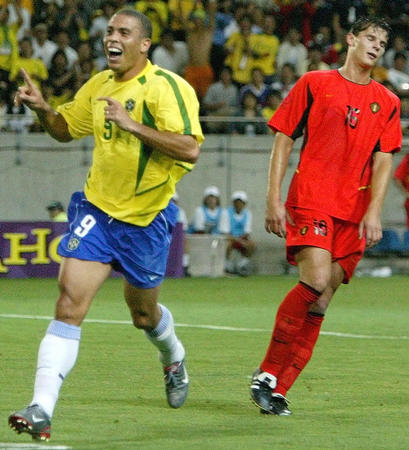 Brazil's goal scorer Ronaldo celebrates the second goal as he runs past against Belgium's Daniel Van Buyten (R) during a second round match at the World Cup Finals in Kobe June 17, 2002. Brazil won the match 2-0