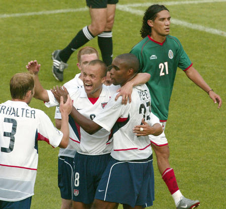 Mexico's Jesus Arellano (back R) walks off the field as USA's (L-R) Gregg Berhalter, Earnie Stewart, Eddie Pope and John O Brien (back) celebrate in a second round match in the World Cup finals in Chonju, June 17, 2002. USA reached the World Cup quarter-finals on Monday after goals by Brian McBride and Landon Donovan upset neighbors Mexico 2-0