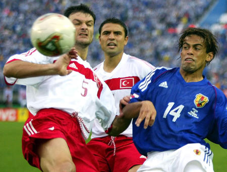 Turkey's Alpay Ozalan (L) and Fatih Akyel (C) challenge Japan's Allesandro Santos (R) for the ball during a second round World Cup Finals match in Sendai June 18, 2002.