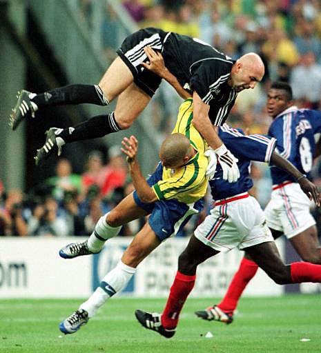 Ronaldo of Brazil, bottom left, crashes into French goalkeeper Fabien Barthez as Lilian Thuram looks on during the final of the soccer World Cup 98 between Brazil and France at the Stade de France in Saint Denis, north of Paris, Sunday July 12, 1998. 